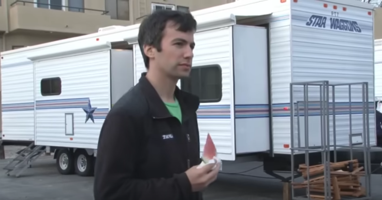 Nathan Fielder holding a thin slice of watermelon